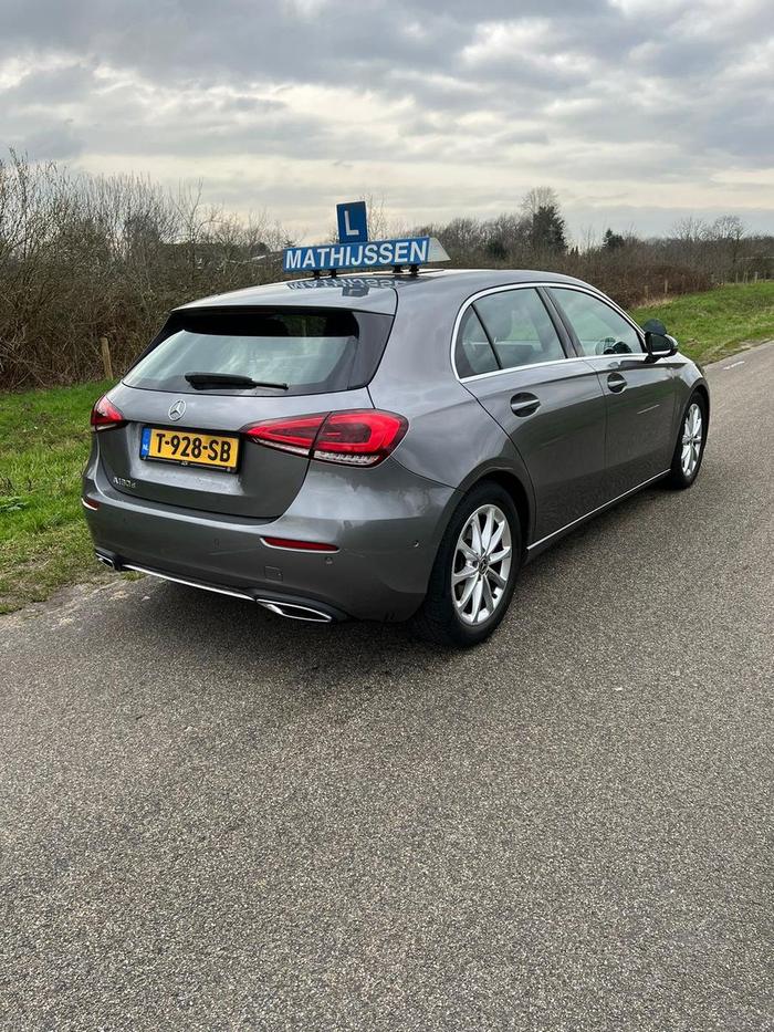 Achterzijde van de lesauto van Autorijschool Mathijssen op een rustige weg